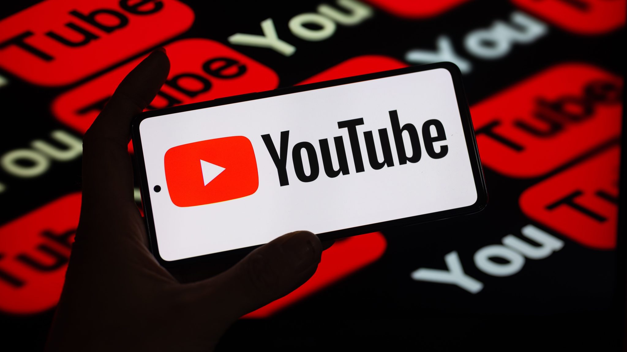 شعار YouTube على شاشة أمام شعارات YouTube أخرى تغطي خلفية سوداء