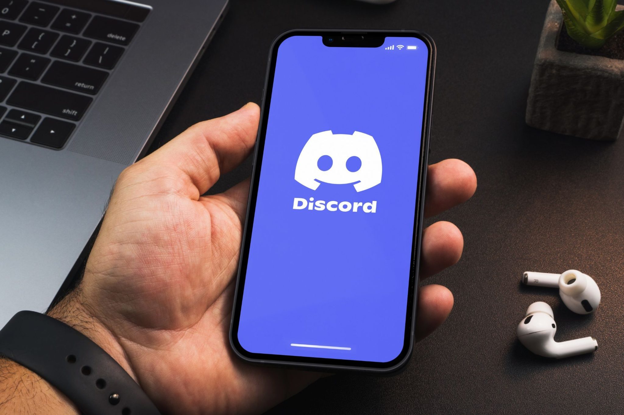 شخص يحمل هاتفًا ذكيًا عليه تطبيق Discord