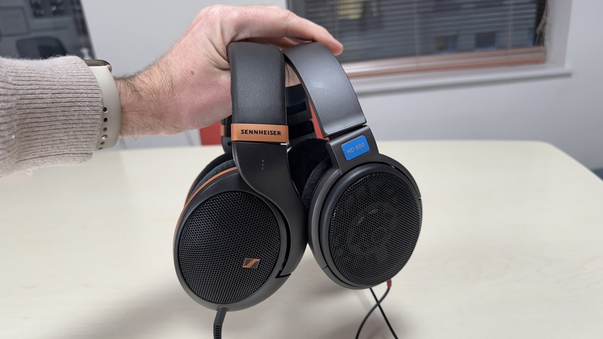 Sennheiser HD 505 and HD 600 headphones held in a man's hand