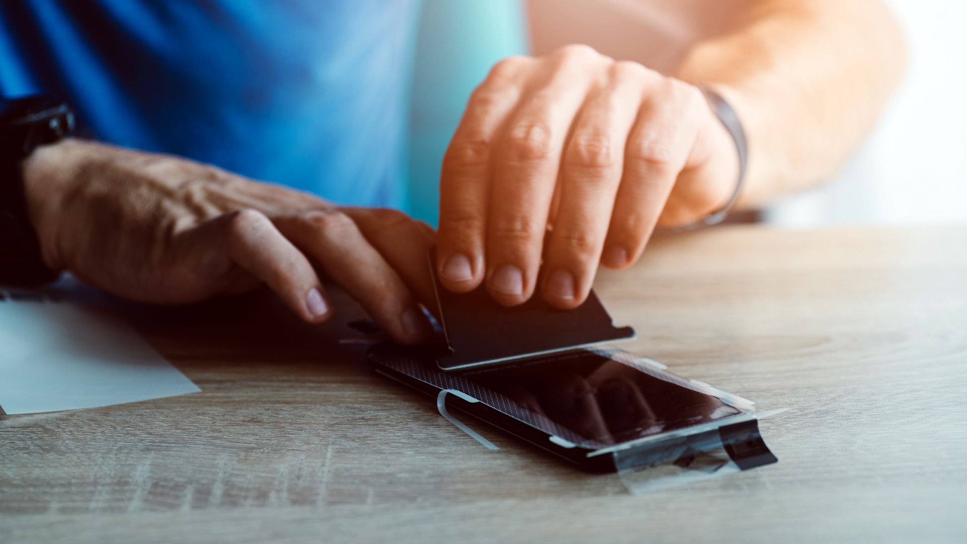 person applying smartphone protector to smartphone screen