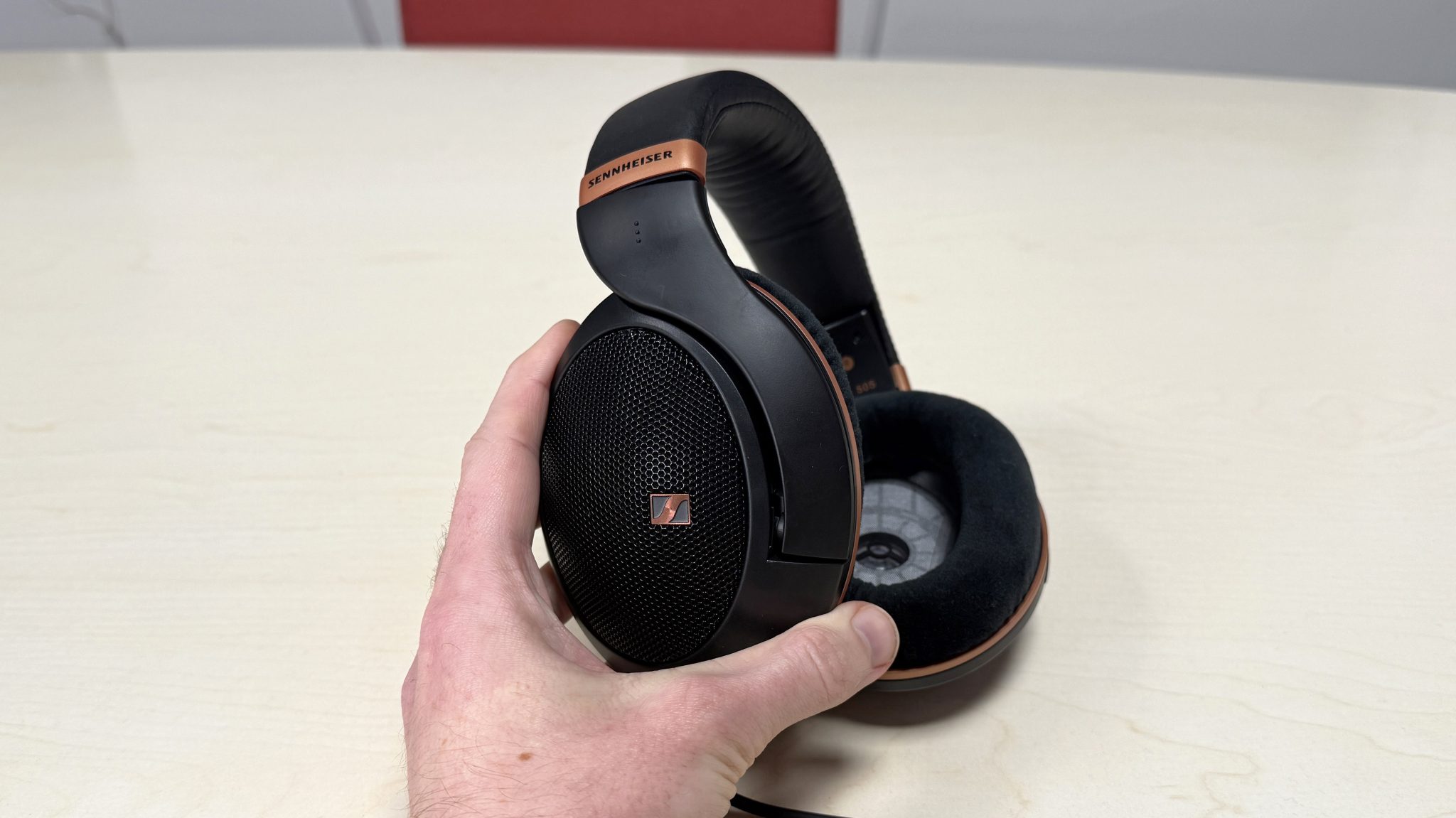 Sennheiser HD 505 headphones held in a man's hand, showing the earcup mesh