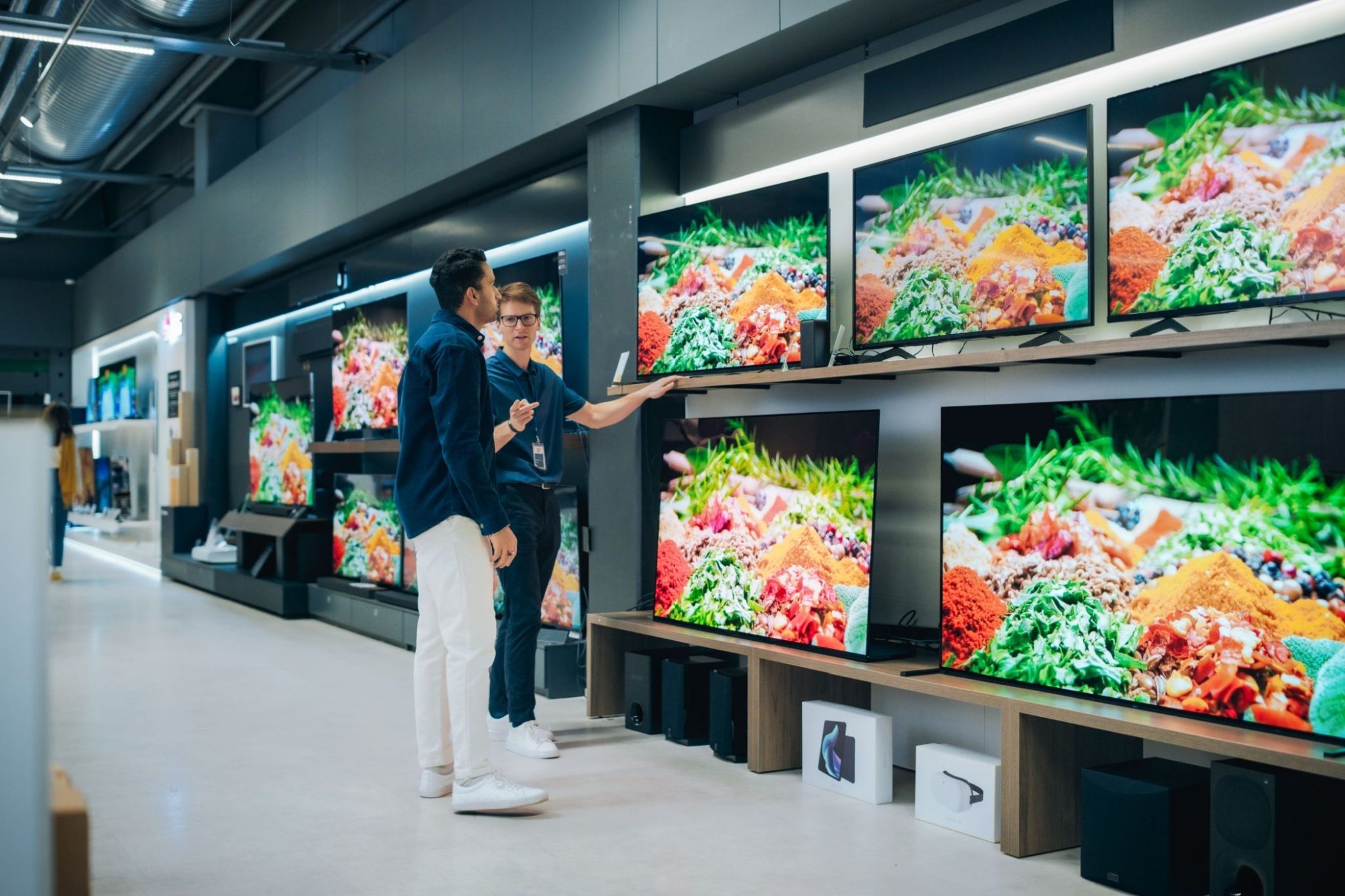 A store employee showing TVs to a customer.