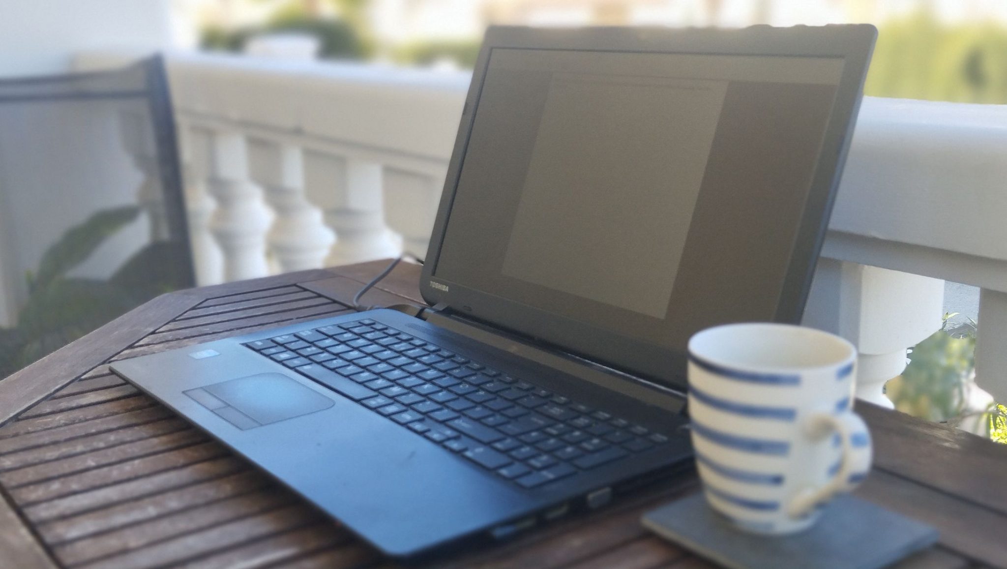 Tosihiba laptop sitting on table with coffee cup