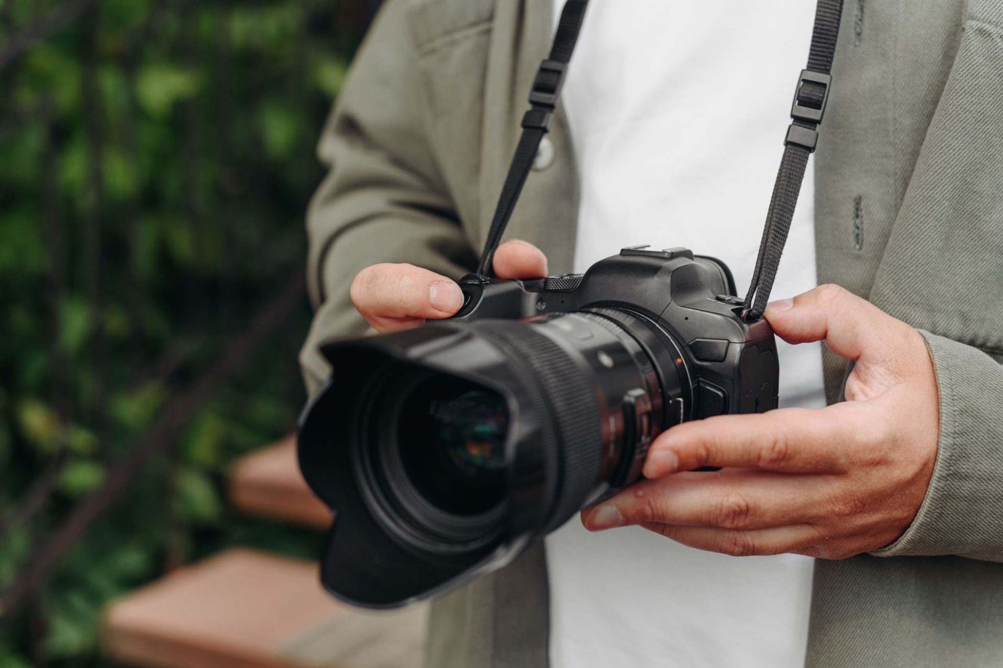 Young adult photographer in white t-shirt holding dslr camera in hands